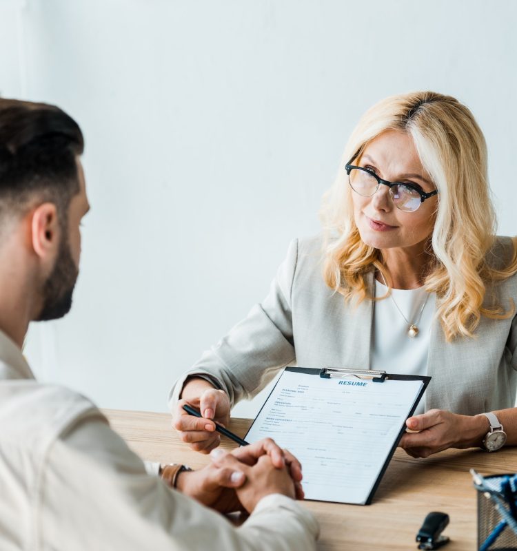 selective-focus-of-recruiter-in-glasses-holding-pen-near-clipboard-and-looking-at-bearded-man-1.jpg